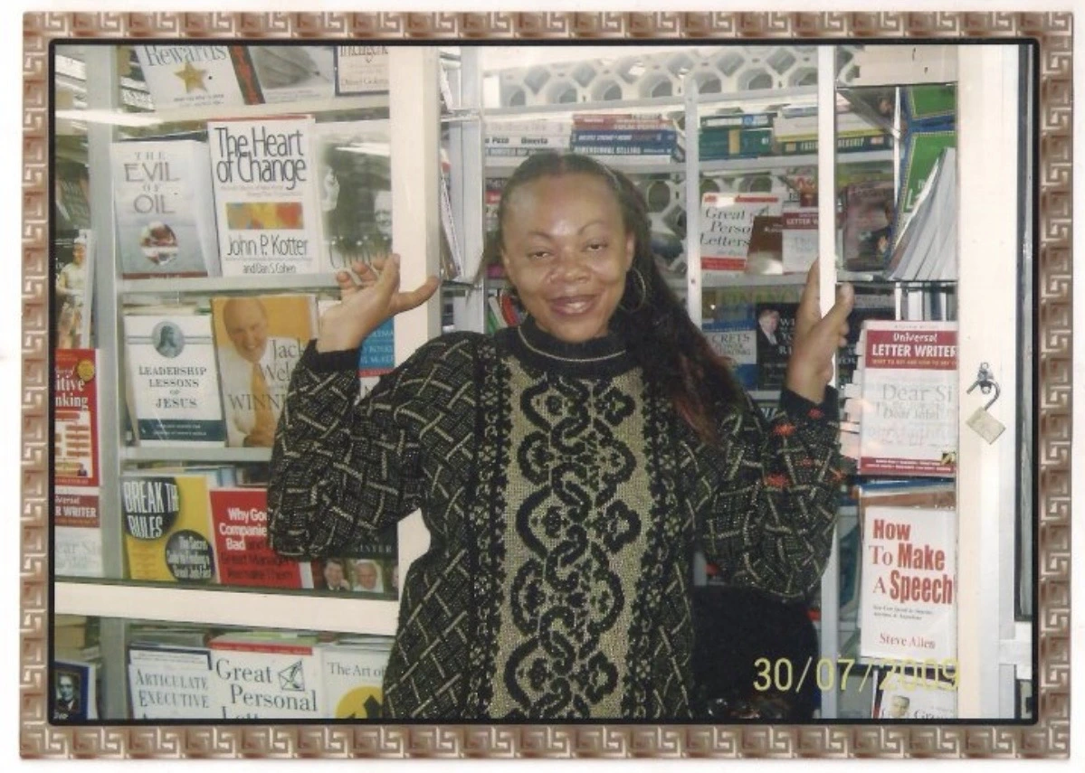 An older framed photograph of a woman standing in front of the bookshop shelves.